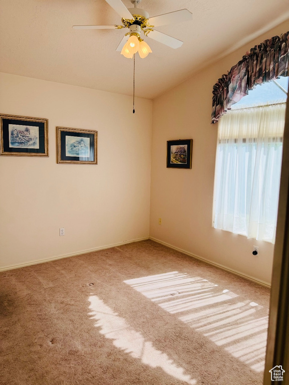 Carpeted empty room with a ceiling fan and baseboards