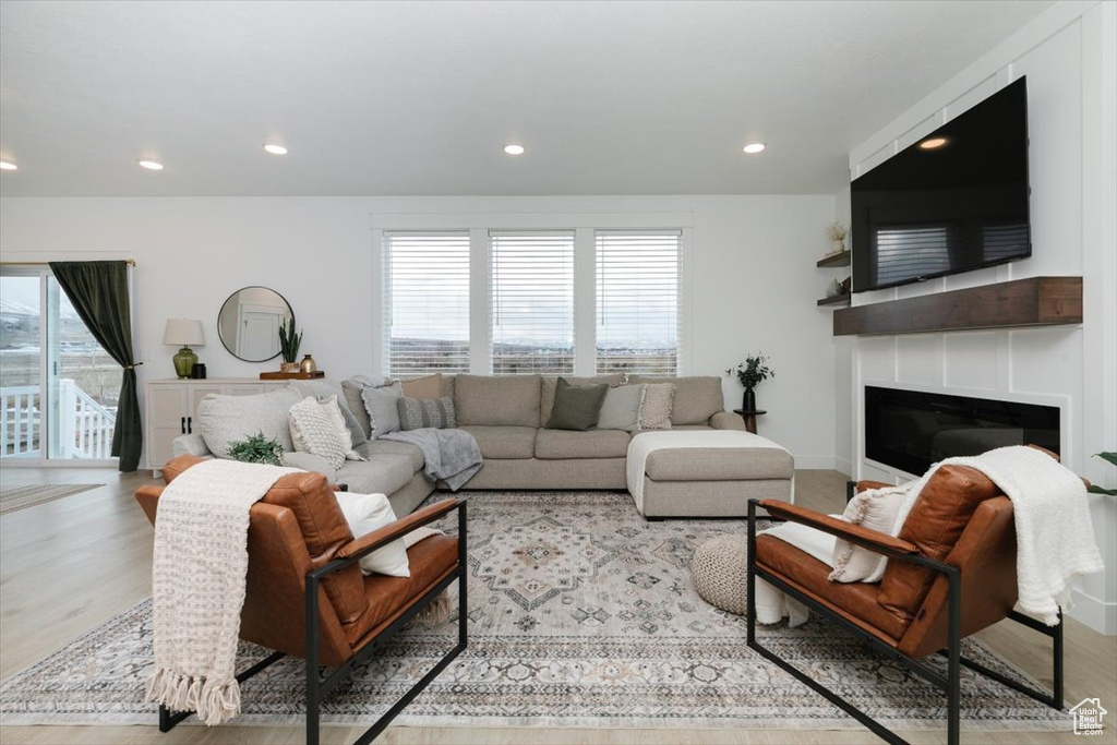 Living room featuring a glass covered fireplace, plenty of natural light, and wood finished floors