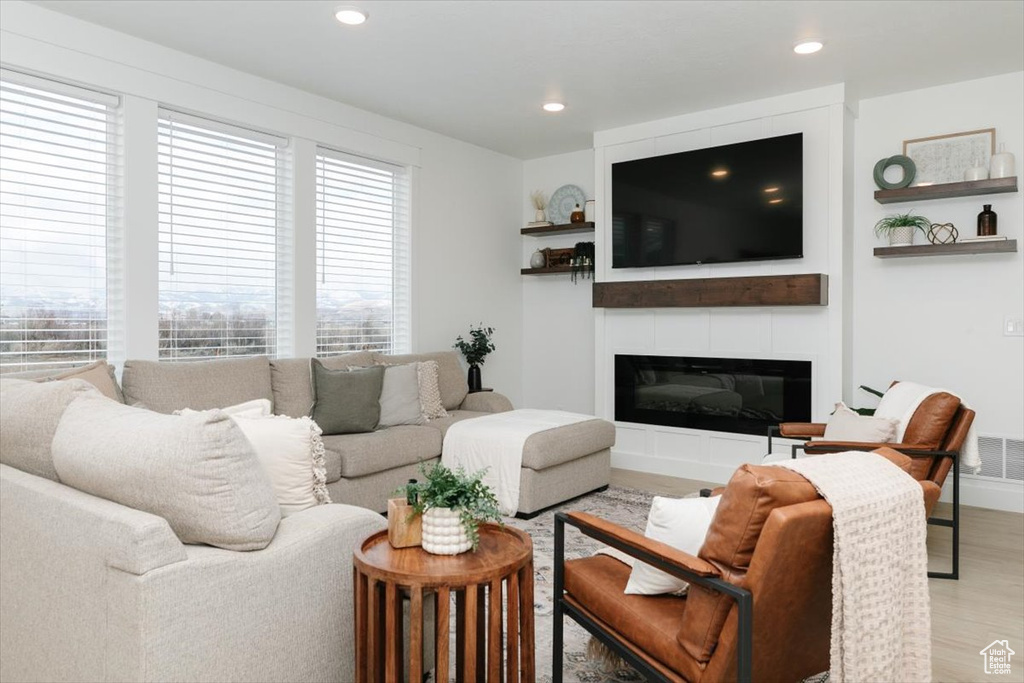 Living room featuring a glass covered fireplace, visible vents, recessed lighting, and wood finished floors