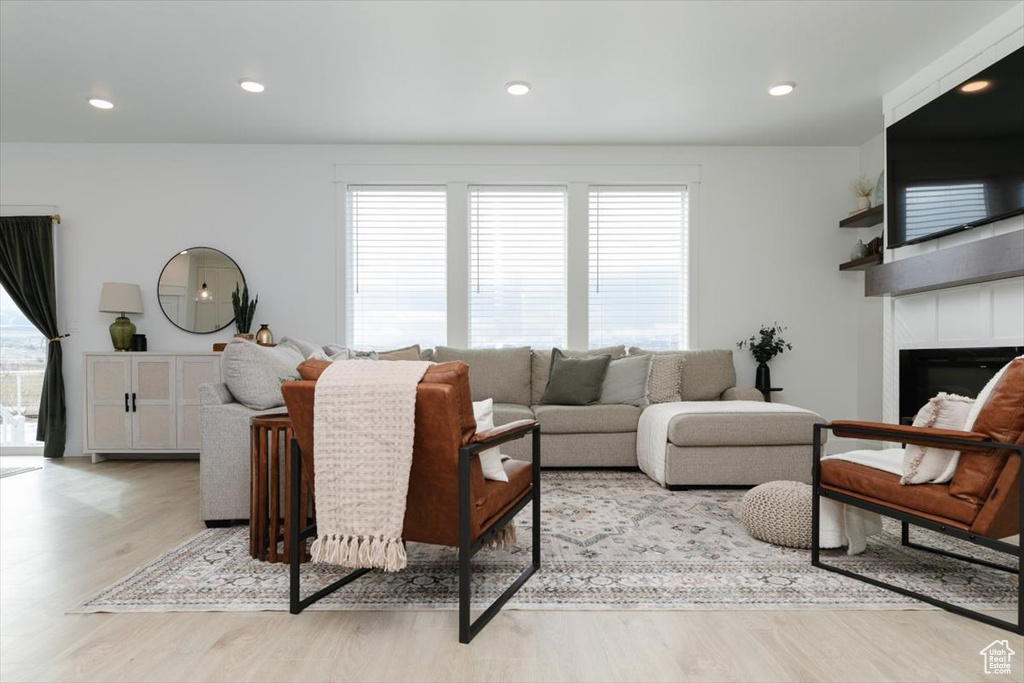 Living area featuring a large fireplace, recessed lighting, a wealth of natural light, and light wood-style floors