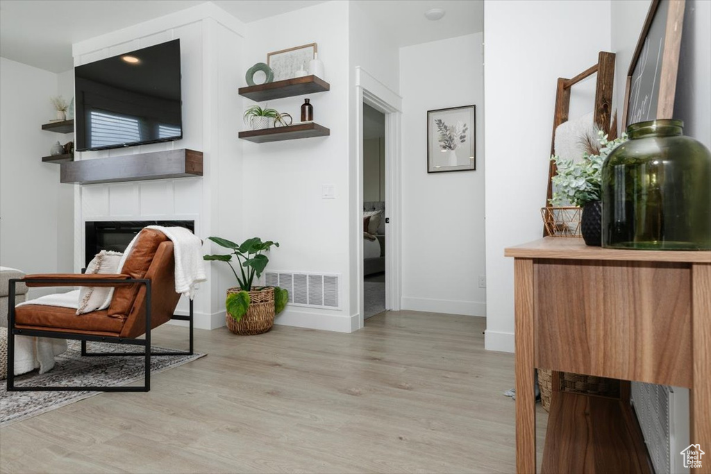 Living area with light wood-type flooring, a fireplace, visible vents, and baseboards