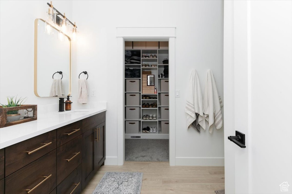 Full bath featuring a spacious closet, wood finished floors, and vanity