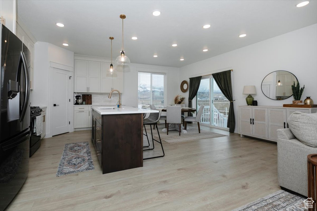 Kitchen with a breakfast bar area, light countertops, open floor plan, a sink, and black appliances