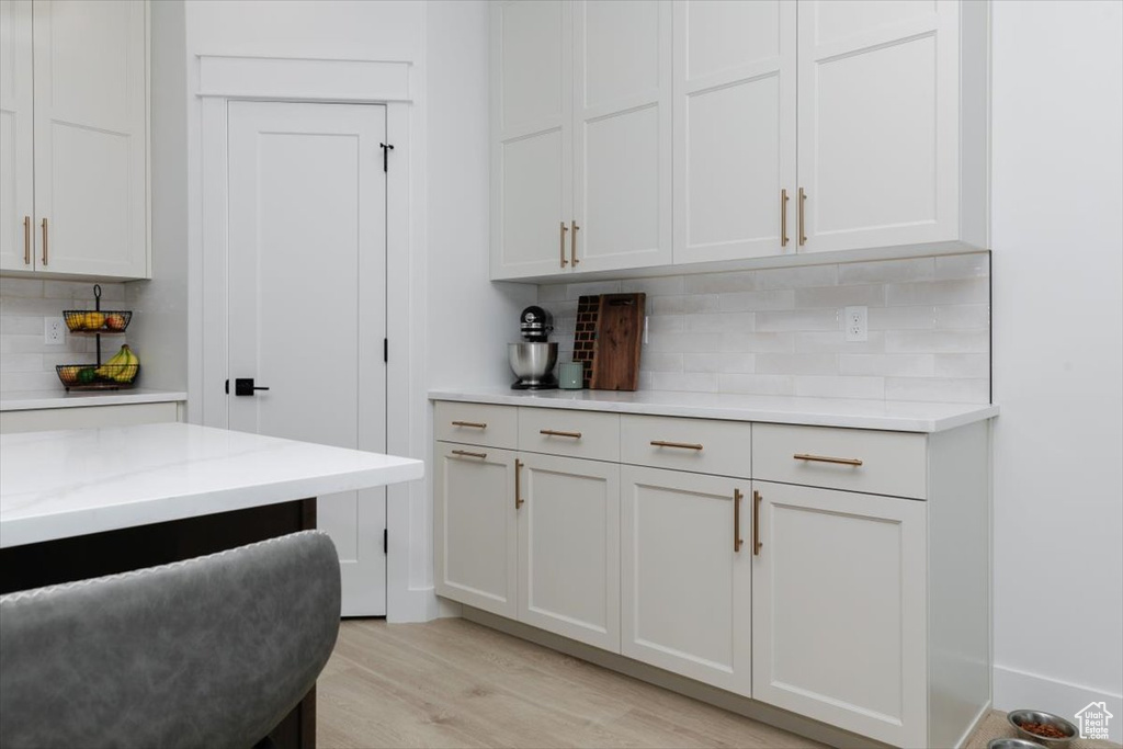 Bar featuring light wood-type flooring and decorative backsplash