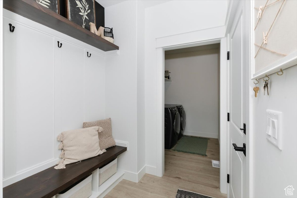 Mudroom with light wood-style flooring, baseboards, and independent washer and dryer