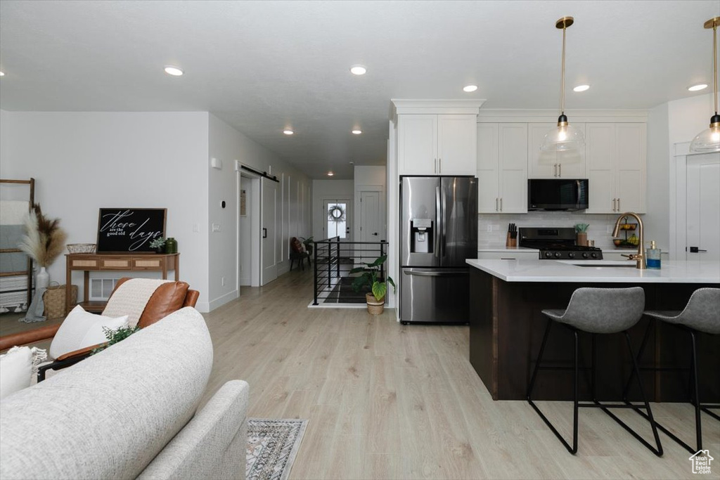 Kitchen featuring stainless steel refrigerator with ice dispenser, a barn door, gas stove, a sink, and black microwave