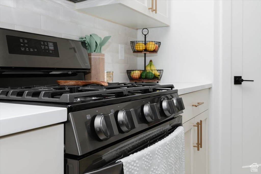 Interior details featuring light countertops, backsplash, and white cabinetry