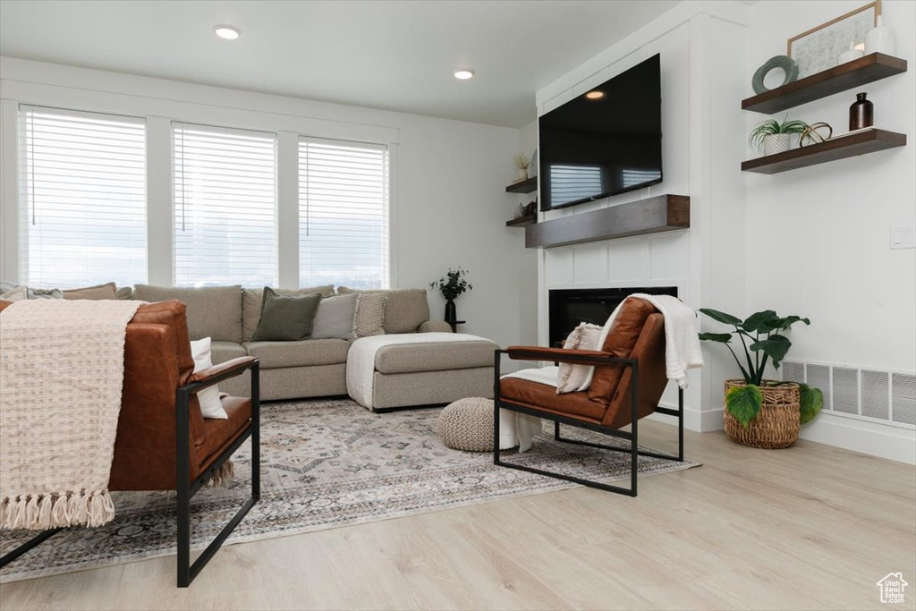 Living room featuring baseboards, visible vents, wood finished floors, a fireplace, and recessed lighting