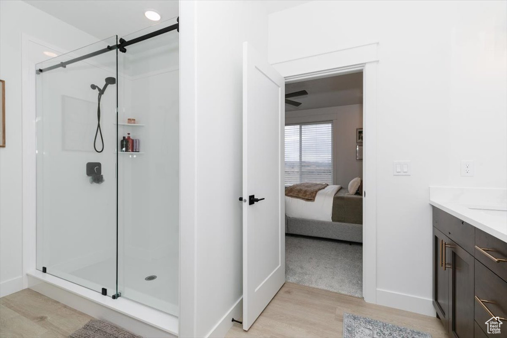 Bathroom featuring a stall shower, connected bathroom, vanity, wood finished floors, and baseboards