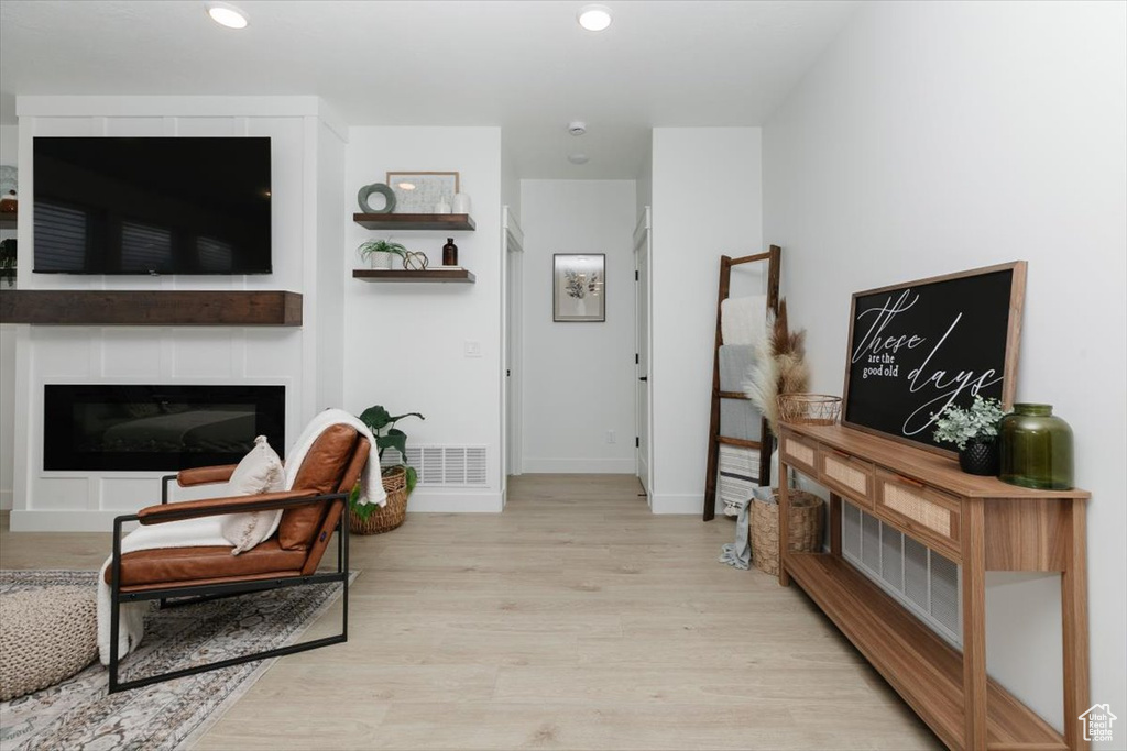 Living area featuring recessed lighting, visible vents, a glass covered fireplace, wood finished floors, and baseboards