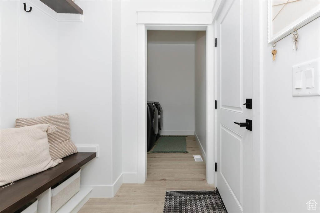 Mudroom with washing machine and clothes dryer, light wood-style flooring, and baseboards