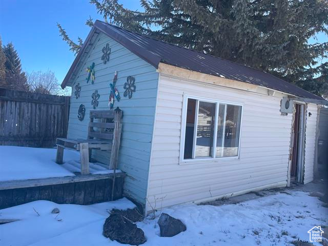 View of snowy exterior featuring an outbuilding and fence