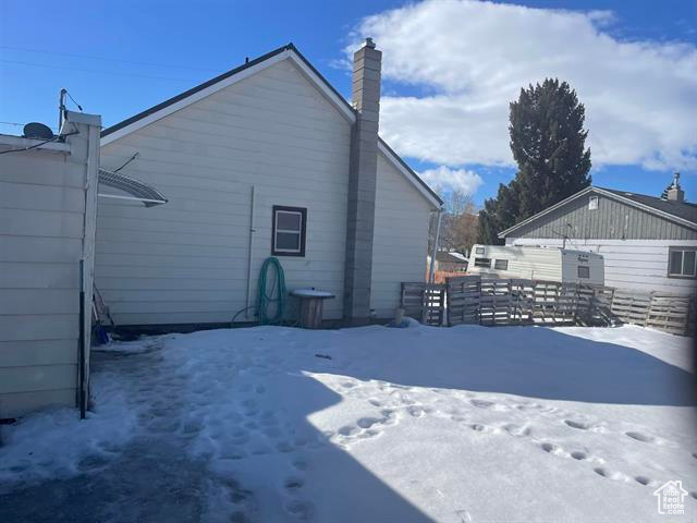 Snow covered property with fence and a chimney