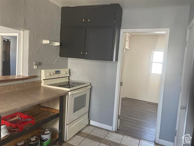 Kitchen with electric range, baseboards, and light tile patterned flooring