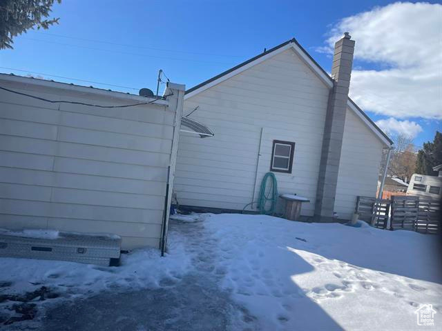 Snow covered back of property featuring fence