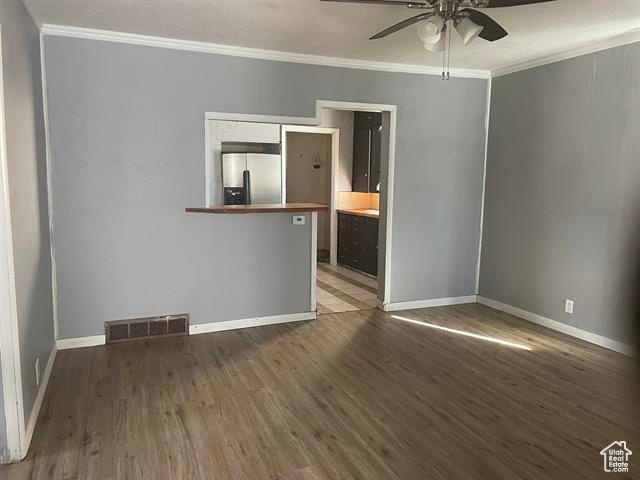 Spare room featuring visible vents, baseboards, a ceiling fan, wood finished floors, and crown molding