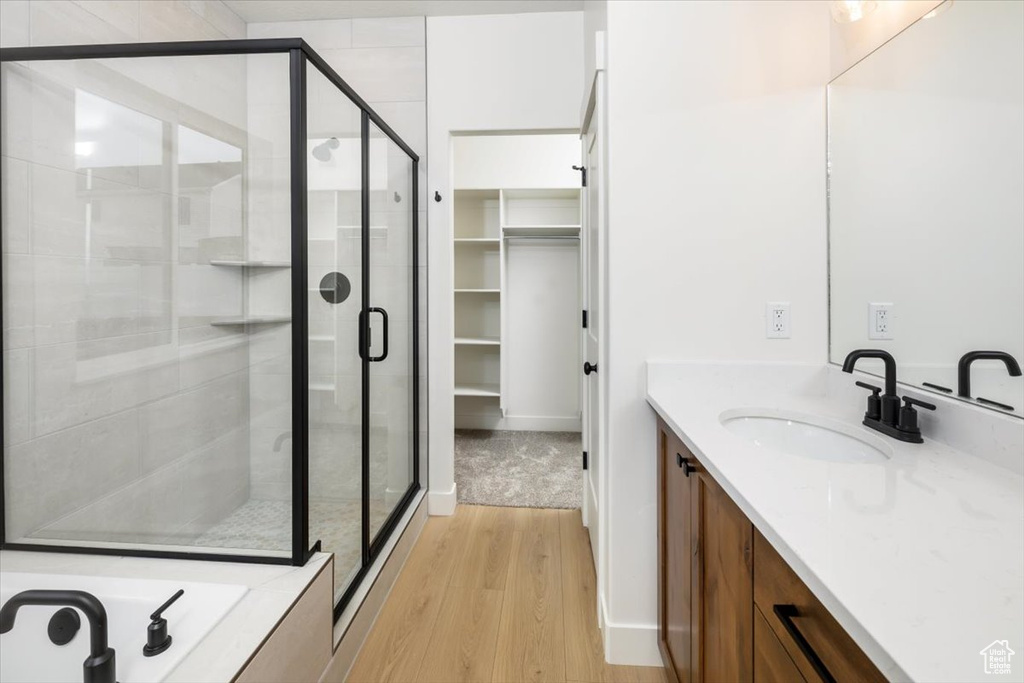 Bathroom featuring a stall shower, a spacious closet, wood finished floors, and vanity