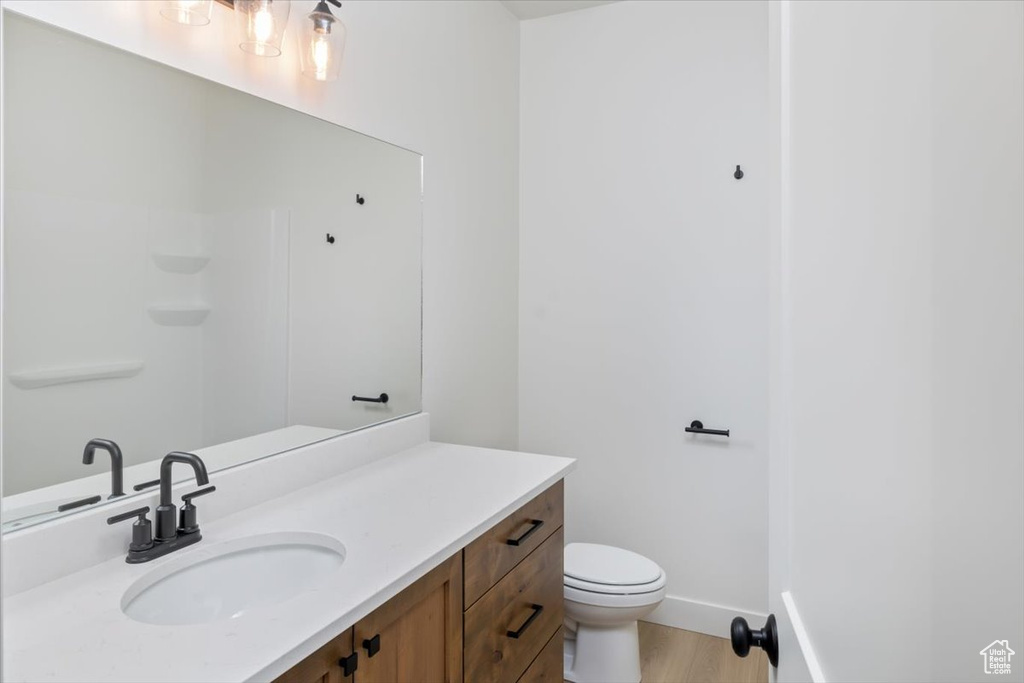 Bathroom featuring toilet, wood finished floors, vanity, and baseboards