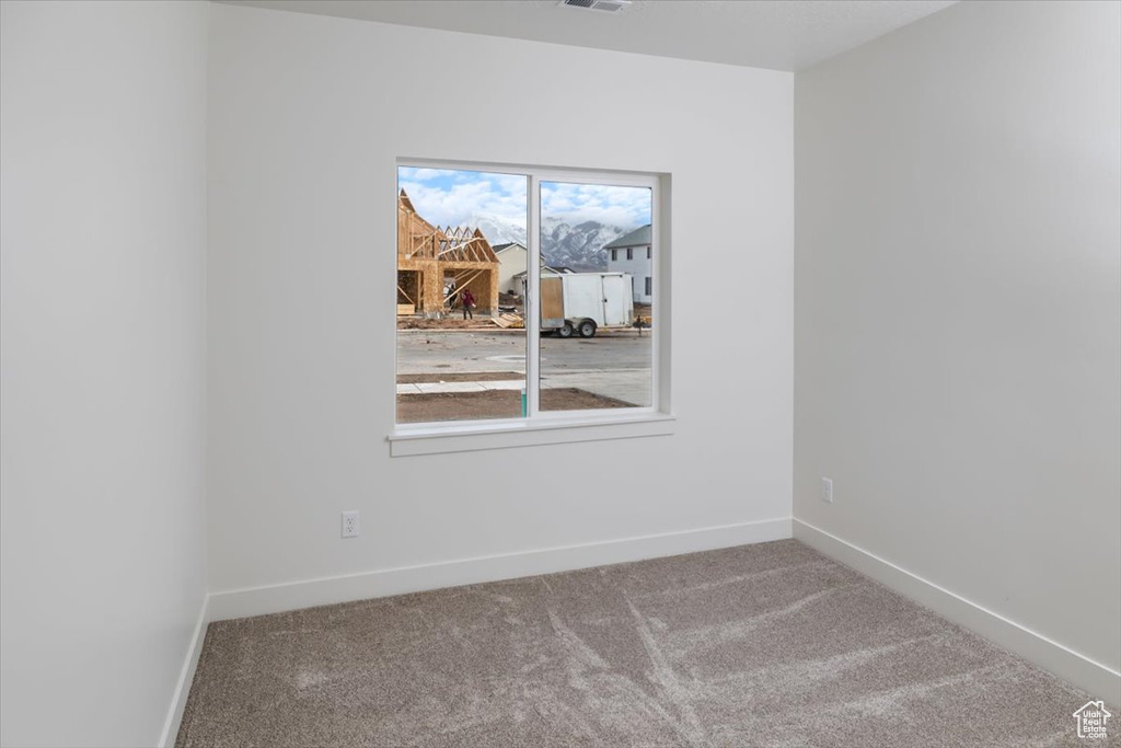 Empty room with carpet, visible vents, and baseboards