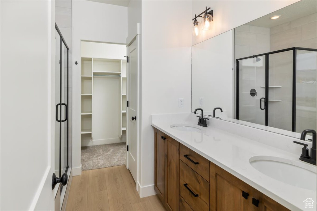 Full bathroom featuring a spacious closet, a stall shower, and a sink