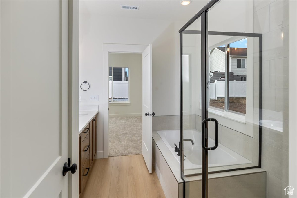 Full bathroom with visible vents, a garden tub, vanity, and wood finished floors