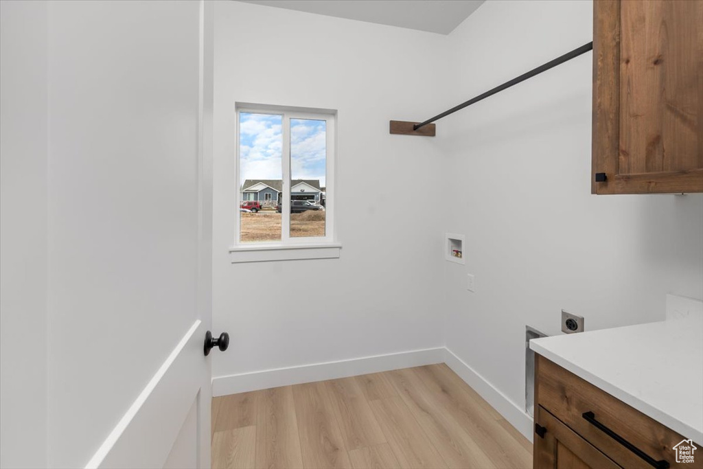 Clothes washing area featuring cabinet space, light wood finished floors, baseboards, washer hookup, and electric dryer hookup