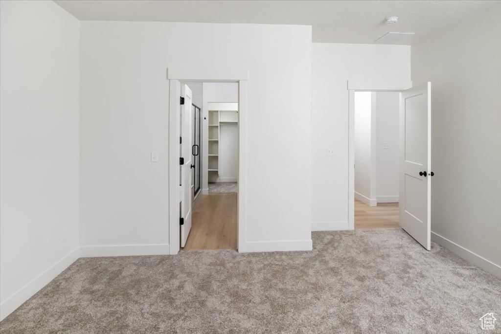 Unfurnished bedroom with carpet flooring, a spacious closet, and baseboards