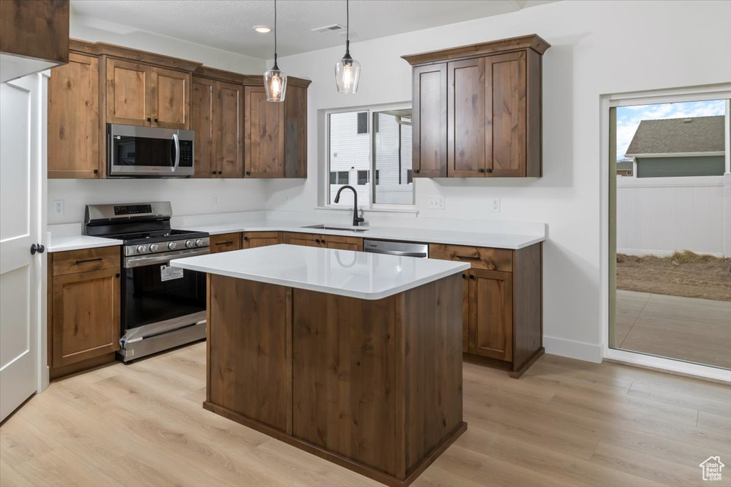 Kitchen featuring a wealth of natural light, light wood-style flooring, stainless steel appliances, and a sink