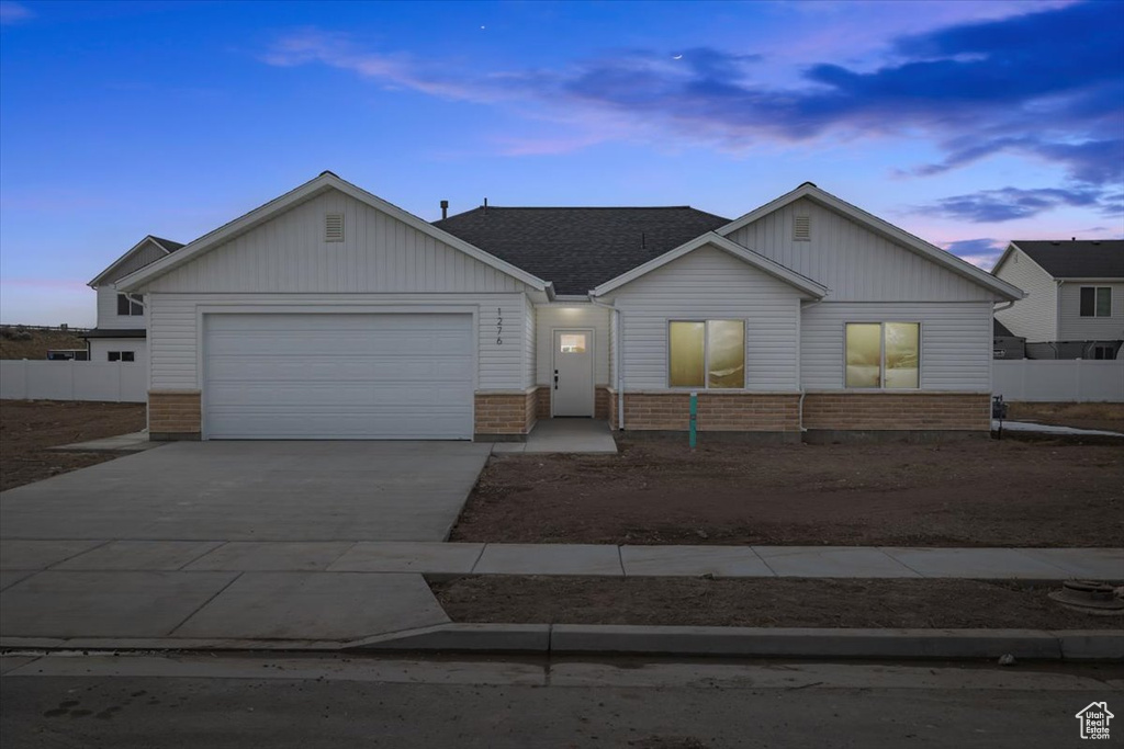 Ranch-style home with concrete driveway, brick siding, fence, and an attached garage