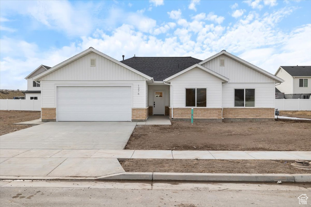 View of front of property featuring a garage, fence, concrete driveway, and brick siding