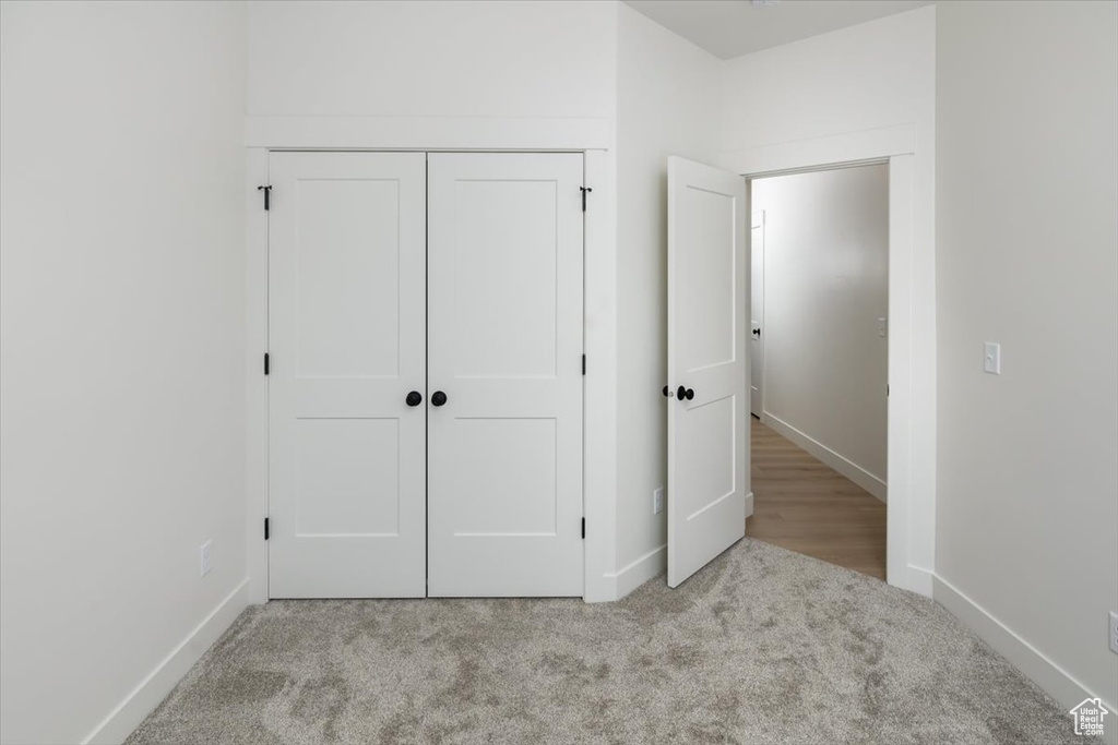 Unfurnished bedroom with carpet, a closet, and baseboards