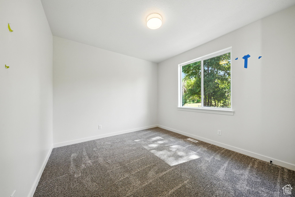 Spare room featuring carpet flooring and baseboards