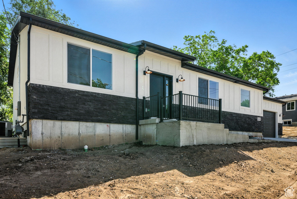 View of front of property featuring an attached garage, board and batten siding, and stone siding
