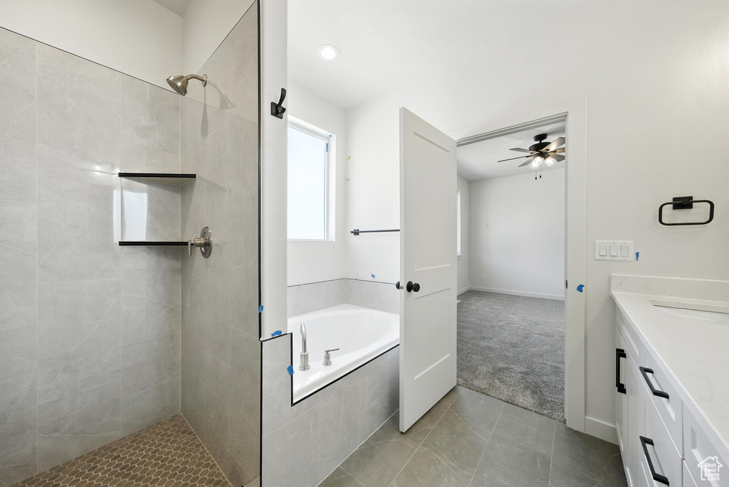 Bathroom with a garden tub, a tile shower, vanity, a ceiling fan, and tile patterned flooring