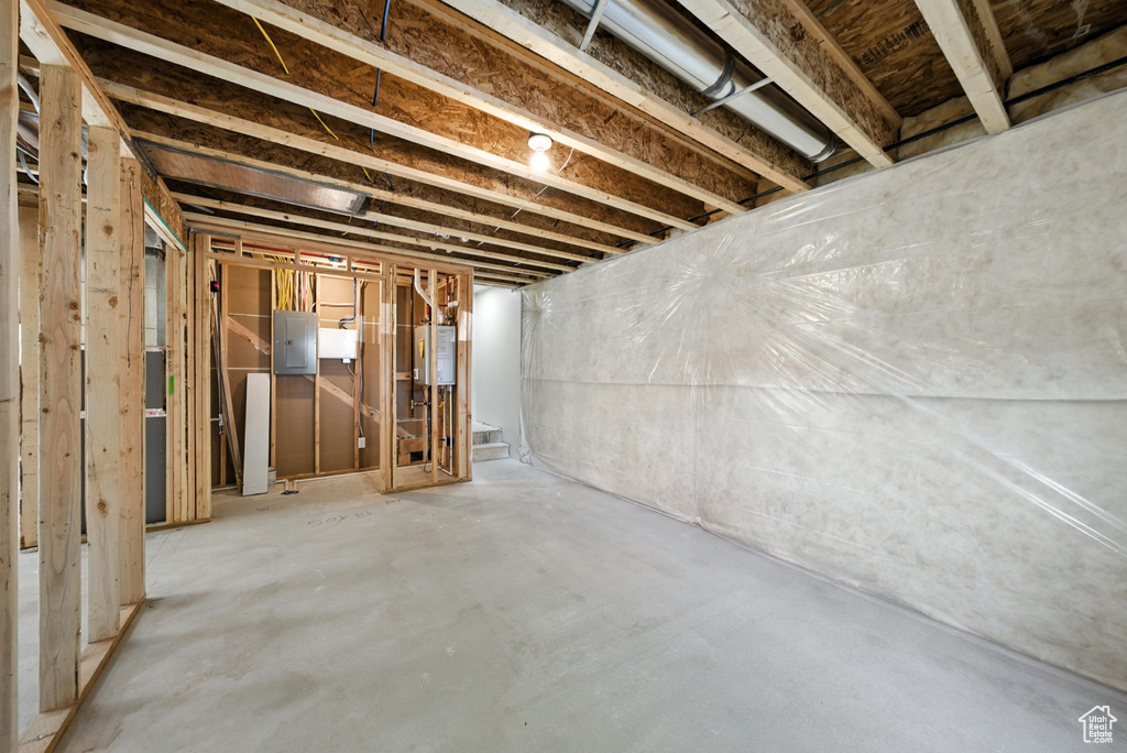 Unfinished basement featuring electric panel and tankless water heater