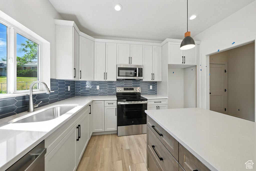 Kitchen featuring stainless steel appliances, backsplash, light countertops, light wood-style floors, and recessed lighting