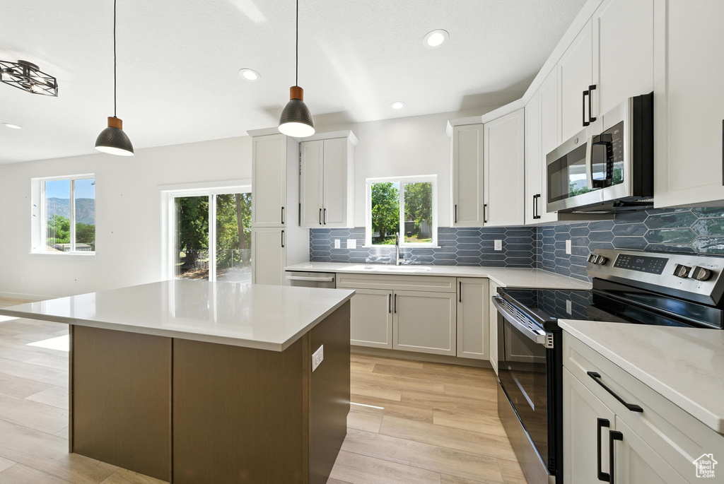 Kitchen with appliances with stainless steel finishes, healthy amount of natural light, backsplash, light wood finished floors, and recessed lighting