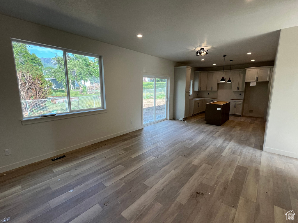 Unfurnished living room featuring light wood finished floors, baseboards, and recessed lighting