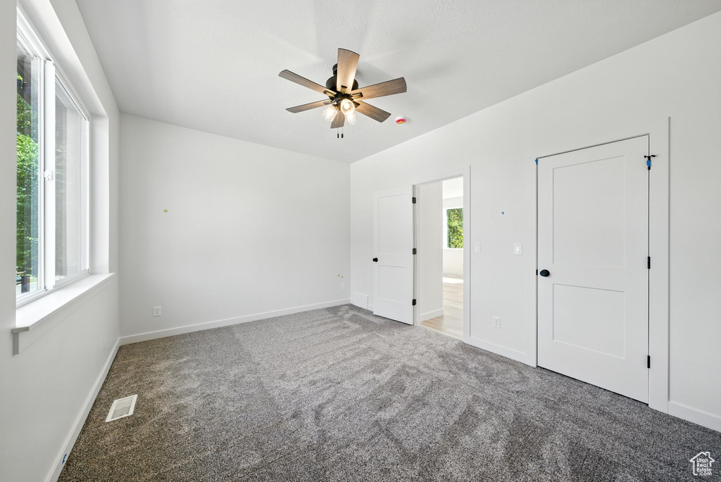 Unfurnished bedroom featuring carpet flooring, a ceiling fan, and ensuite bathroom