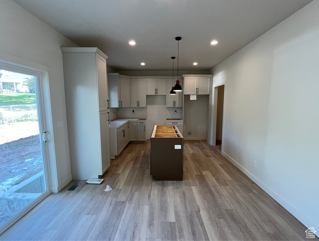 Kitchen featuring a center island, light wood-style flooring, recessed lighting, white cabinetry, and baseboards