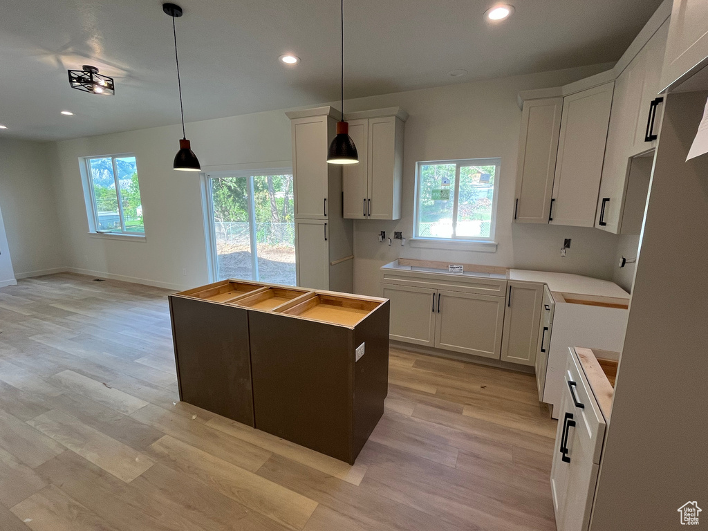 Kitchen featuring recessed lighting, a kitchen island, light wood finished floors, decorative light fixtures, and white cabinetry