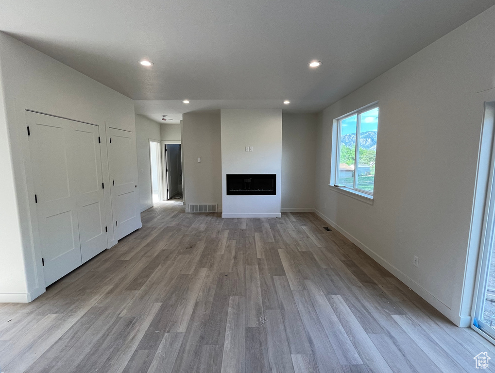 Unfurnished living room with light wood finished floors, recessed lighting, a fireplace, and baseboards