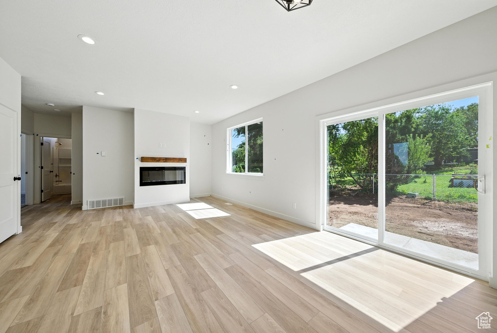 Unfurnished living room with light wood-style flooring, a glass covered fireplace, and recessed lighting