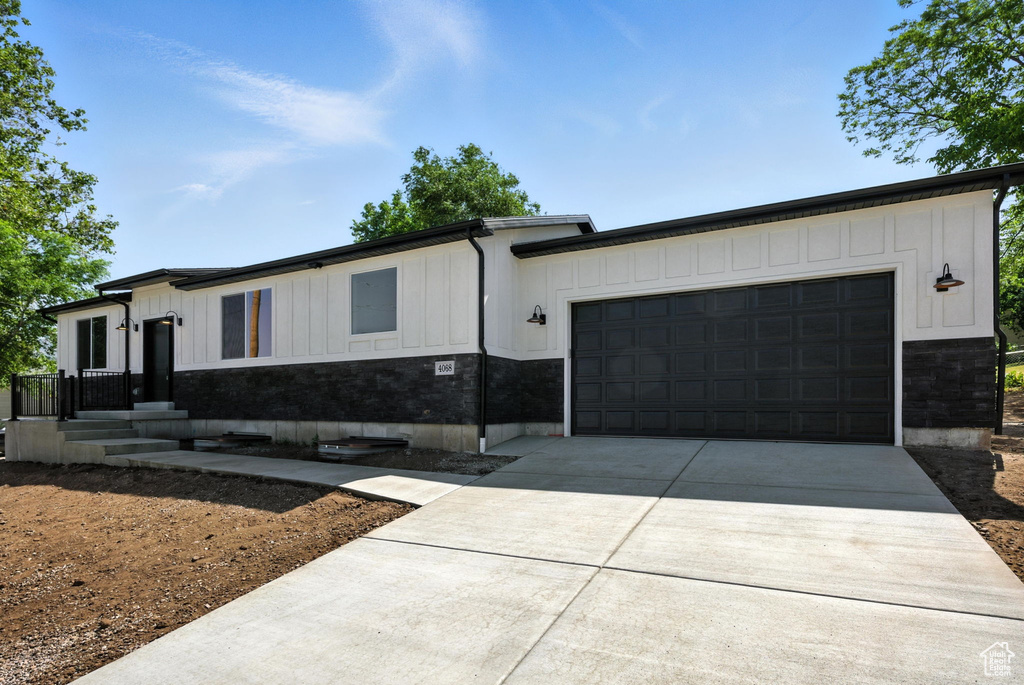 View of front of home featuring board and batten siding, driveway, and a garage