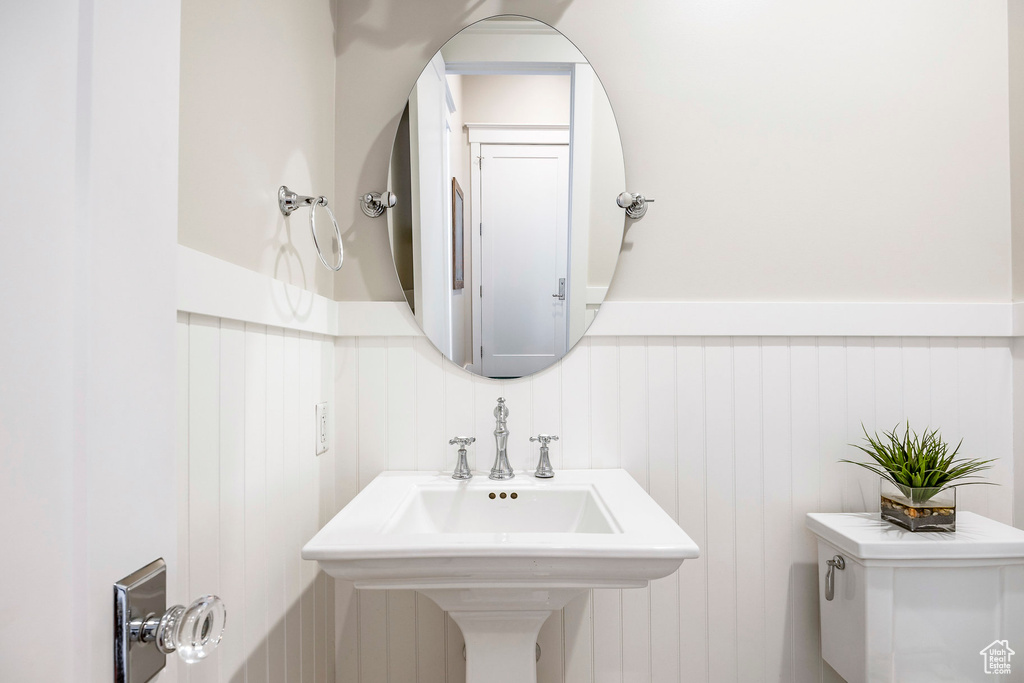 Bathroom featuring wainscoting, a decorative wall, and a sink