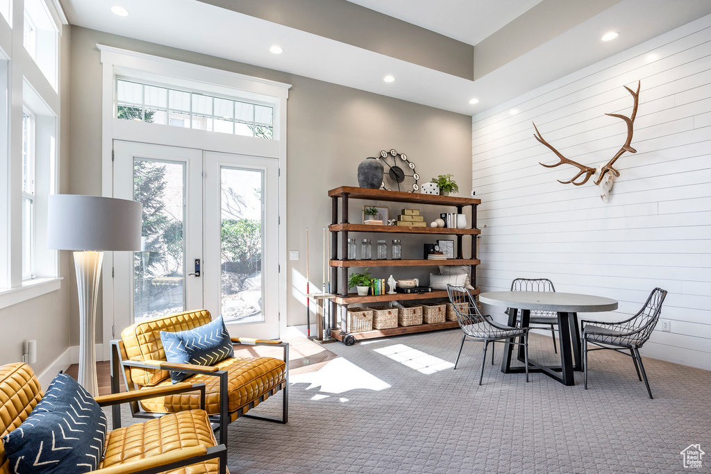 Dining space with healthy amount of natural light, recessed lighting, carpet floors, and wood walls