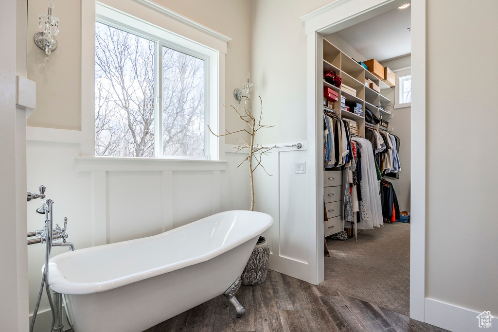 Full bath with a freestanding bath, a spacious closet, and wood finished floors