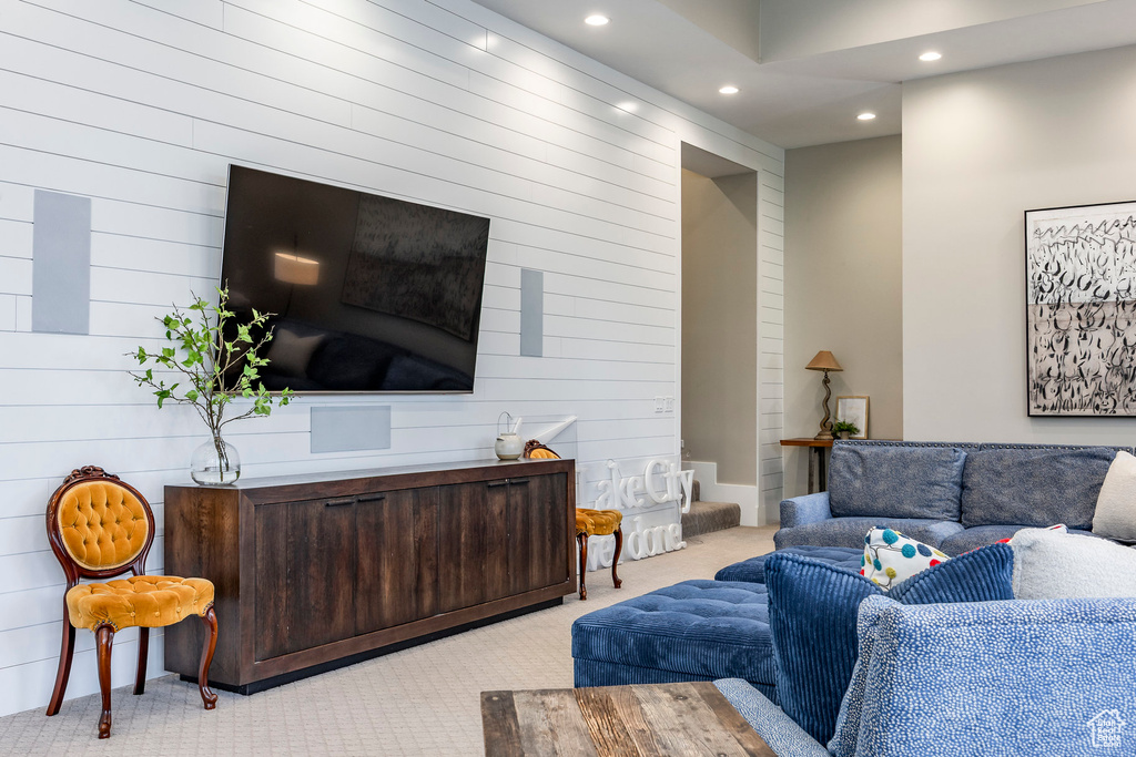 Living room with carpet flooring, recessed lighting, and wooden walls