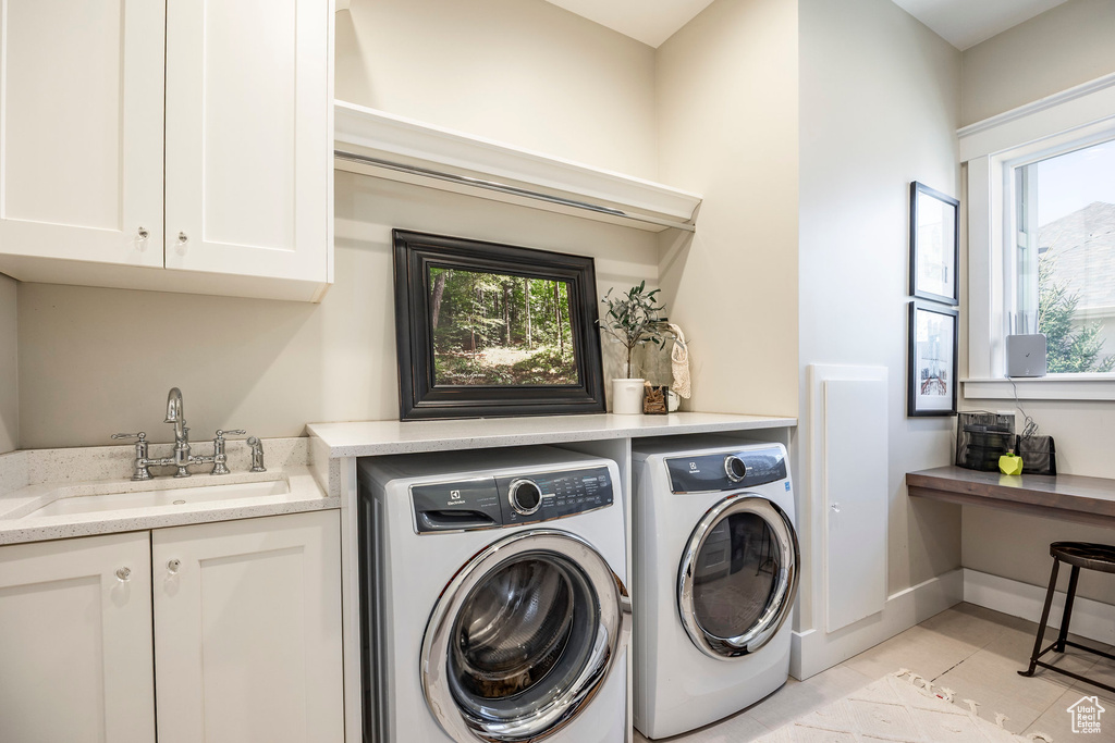 Laundry room featuring washer and clothes dryer, cabinet space, plenty of natural light, and light tile patterned floors