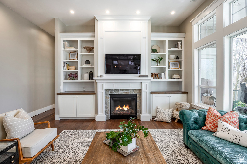 Living area featuring dark wood-style flooring, a tiled fireplace, baseboards, and recessed lighting